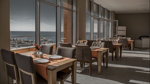A dining area with large windows, a view of the ocean, and a modern interior design. - Legend Business Hotel Batumi (Batumi)