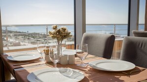A dining table set for two with white plates, wine glasses, and a vase with flowers. - Legend Business Hotel Batumi (Batumi)