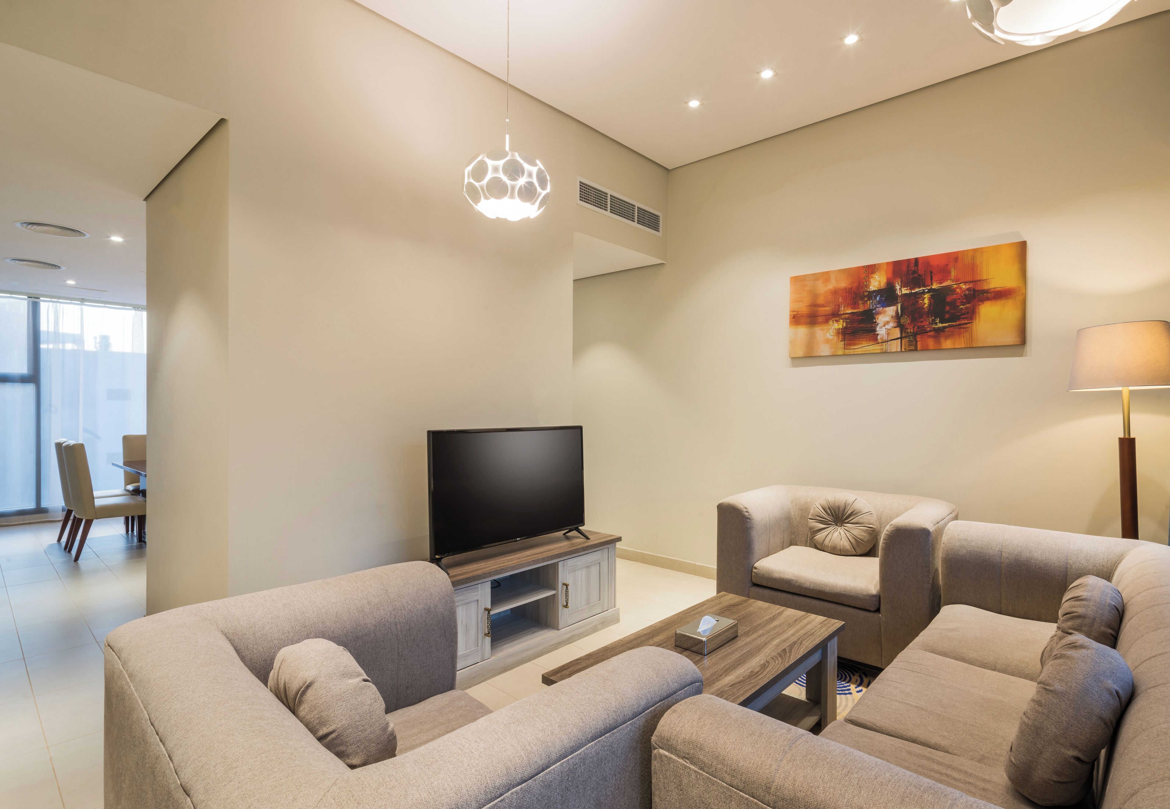 Una sala de estar moderna con un televisor de pantalla plana, dos sofás, una mesa de centro y un cuadro en la pared.