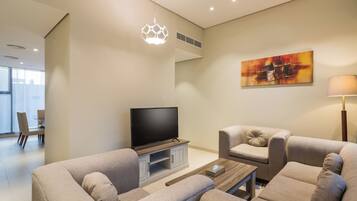 Una sala de estar moderna con un televisor de pantalla plana, dos sofás, una mesa de centro y un cuadro en la pared.