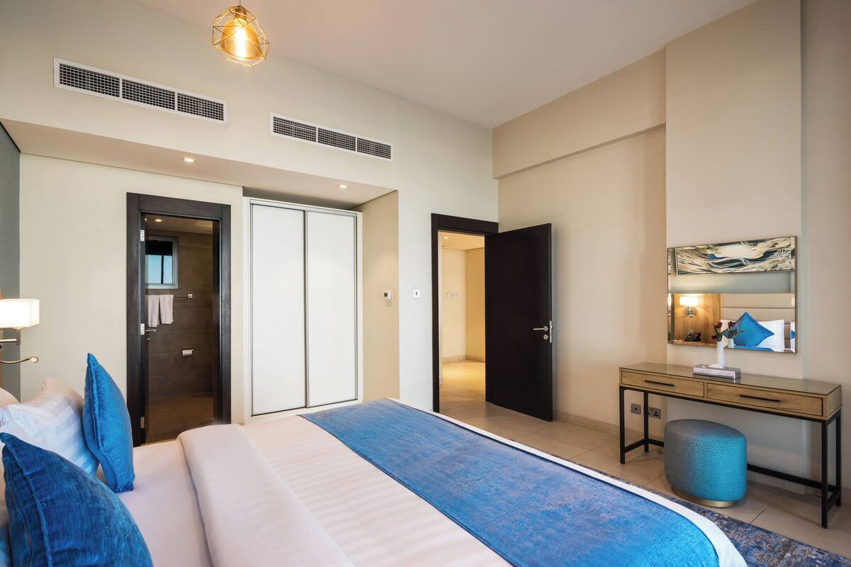 Ett modernt hotellrum med en stor säng, ett skrivbord och en rymlig klädkammare.
