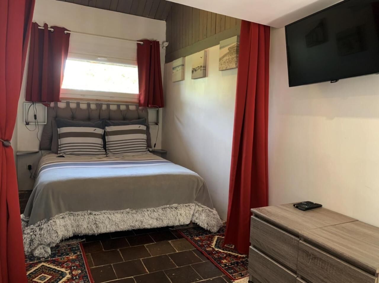 A bedroom with a bed, a TV, and a dresser.