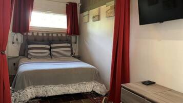 A bedroom with a bed, a TV, and a dresser.