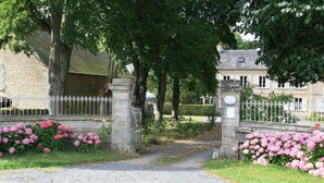 A gravel path leading to a gated entrance with a stone wall and metal fence. - La Part des Anges (Rubercy)