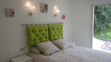 A bedroom with a green tufted headboard, floral bedding, and two wall-mounted light fixtures.