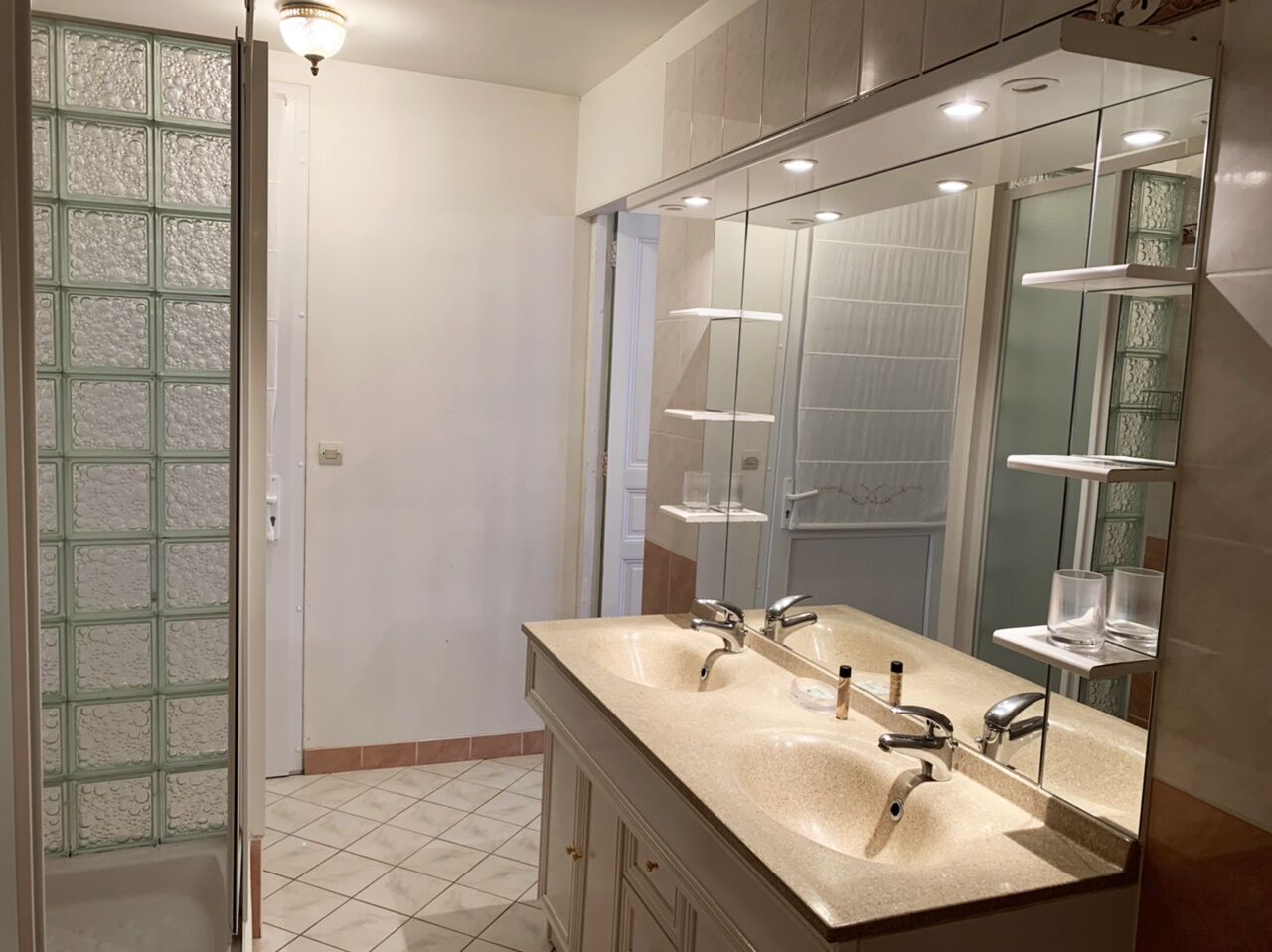 A bathroom with two sinks, a large mirror, and a glass shower enclosure.