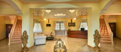 A spacious lobby with a reception desk, a staircase, and a seating area.