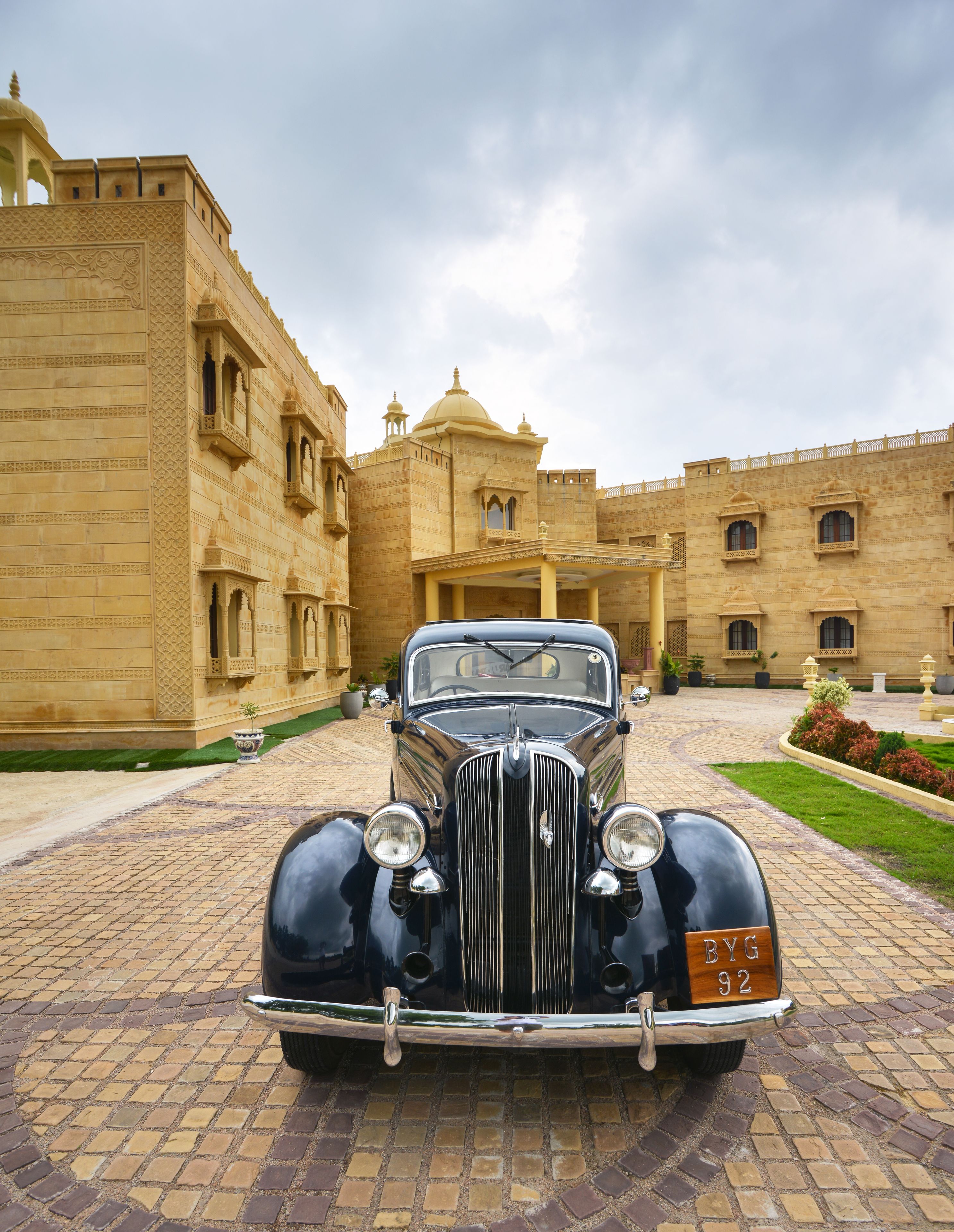 A vintage car parked in front of a historic building with intricate architecture.