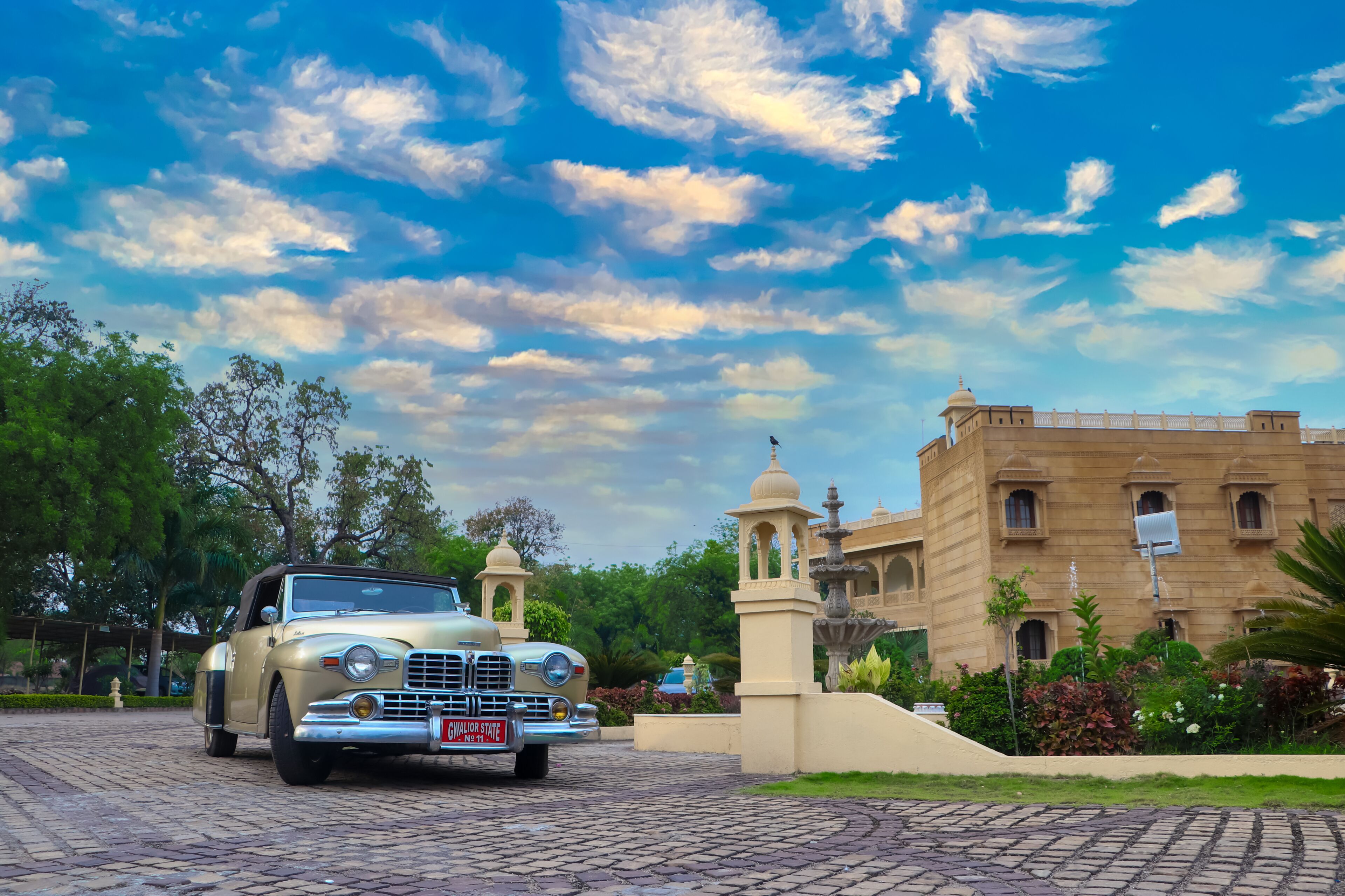 A vintage car parked in front of a historic building with a clear sky.