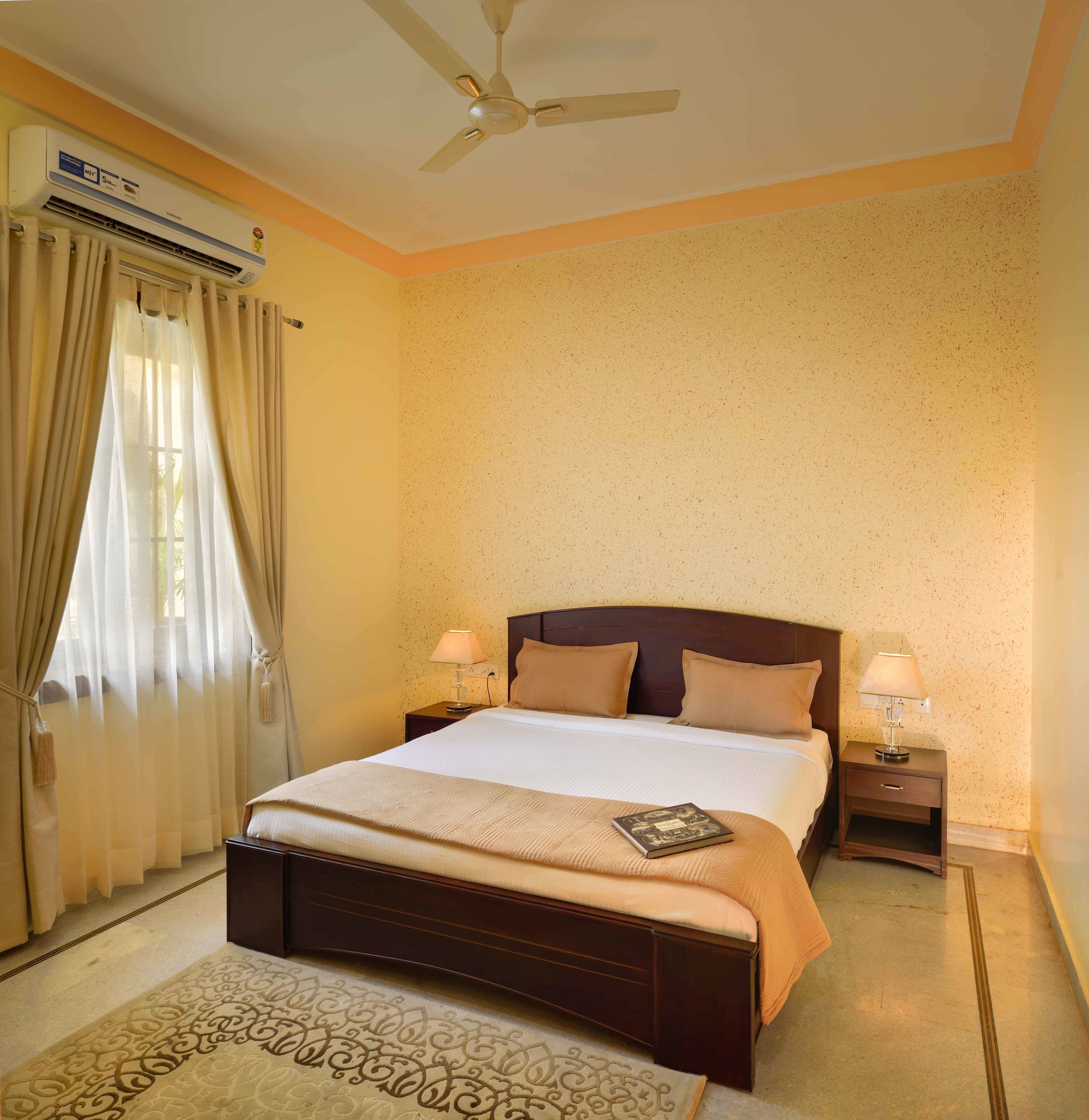 Une chambre d’hôtel équipée d’un lit, de deux lampes de chevet, d’un ventilateur de plafond et d’un appareil de climatisation.