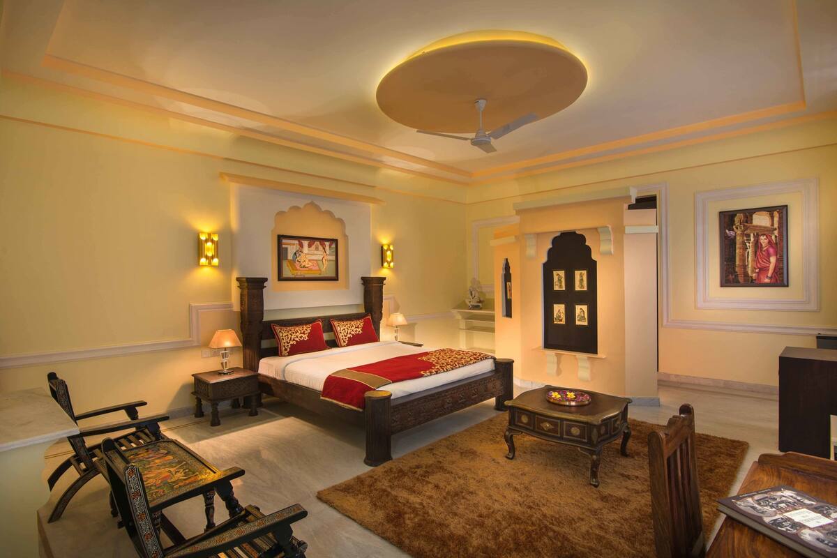 A bedroom with a bed, bedside tables, a chair, a small table, and a ceiling fan.