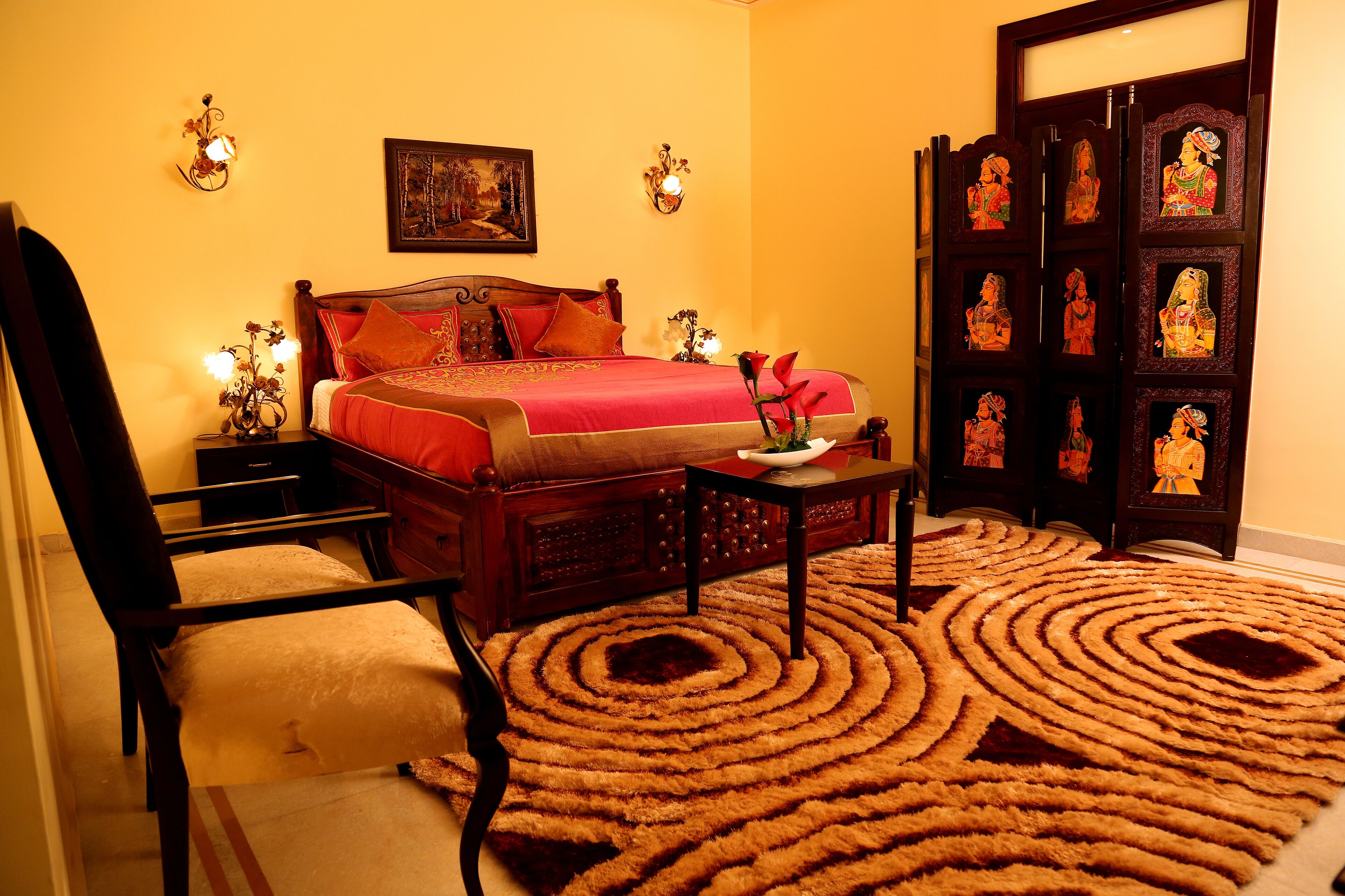 Une chambre à coucher avec un grand lit, une table de chevet en bois, une chaise, une table basse et un tapis décoratif.