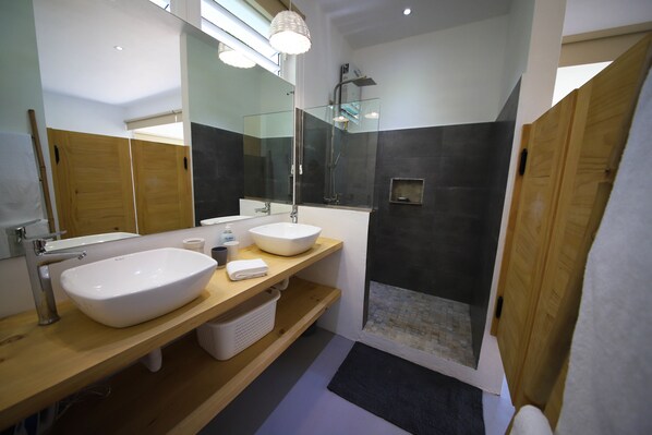 Un baño moderno con dos lavamanos, un espejo grande y una zona de ducha.