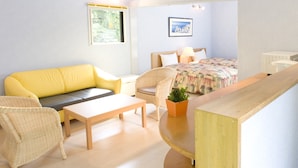 Un dormitorio con cama, sofá, sillón, mesita de noche y ventana.