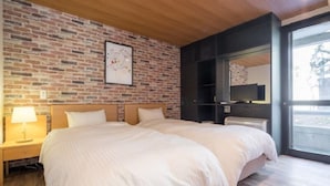 Una cama doble con cabecera de madera, una mesita de noche con lámpara, pared con diseño de ladrillo, un espejo grande y vistas al exterior a través de una puerta de cristal.