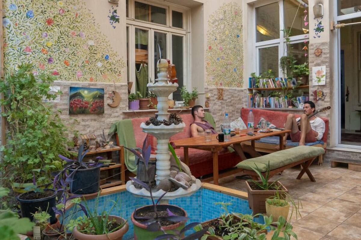 A cozy patio with a fountain, potted plants, and a seating area with a table and chairs.