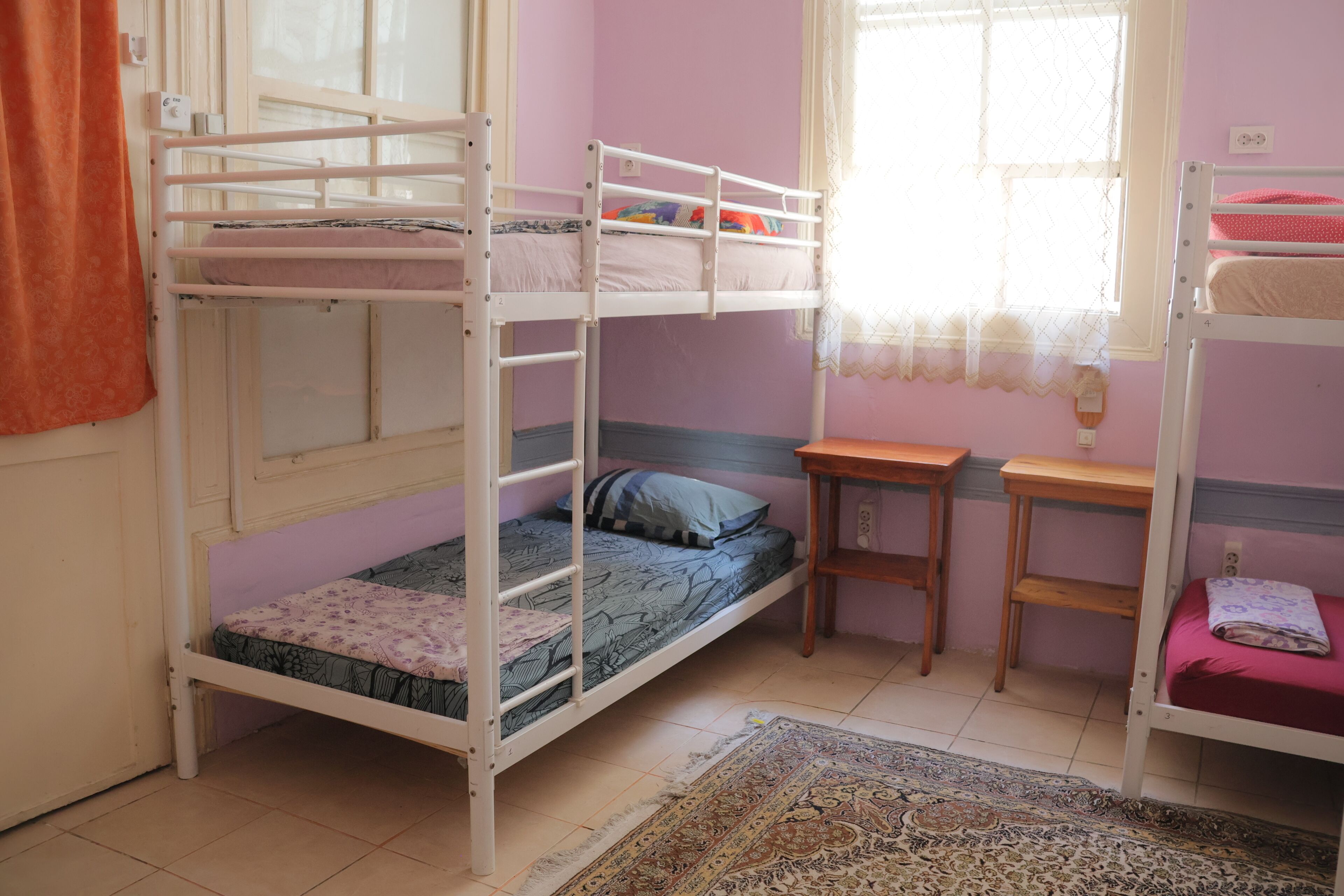 Habitación con literas, una ventana, una mesita pequeña y una alfombra.
