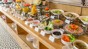Ein Buffet mit verschiedenen Speisen und Getränken, darunter Früchte, Salate und Sushi.