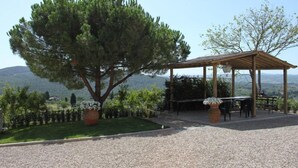 A gazebo with a table and chairs, surrounded by a gravel area and a large tree. - Fattoria Albanese Labardi (Lastra a Signa)