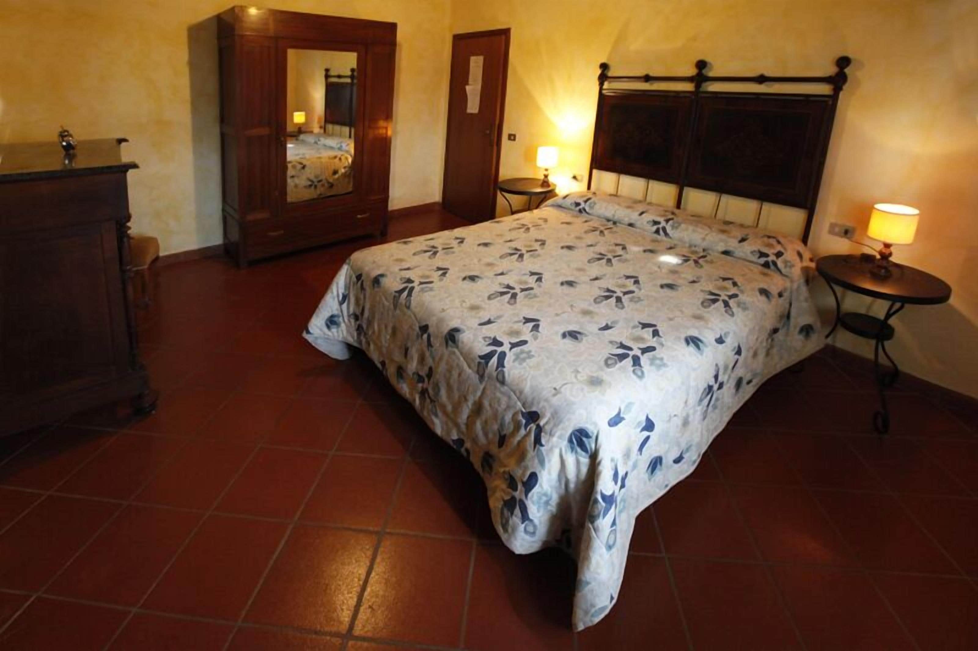 A bedroom with a bed, a dresser, a mirror, and two bedside tables with lamps.