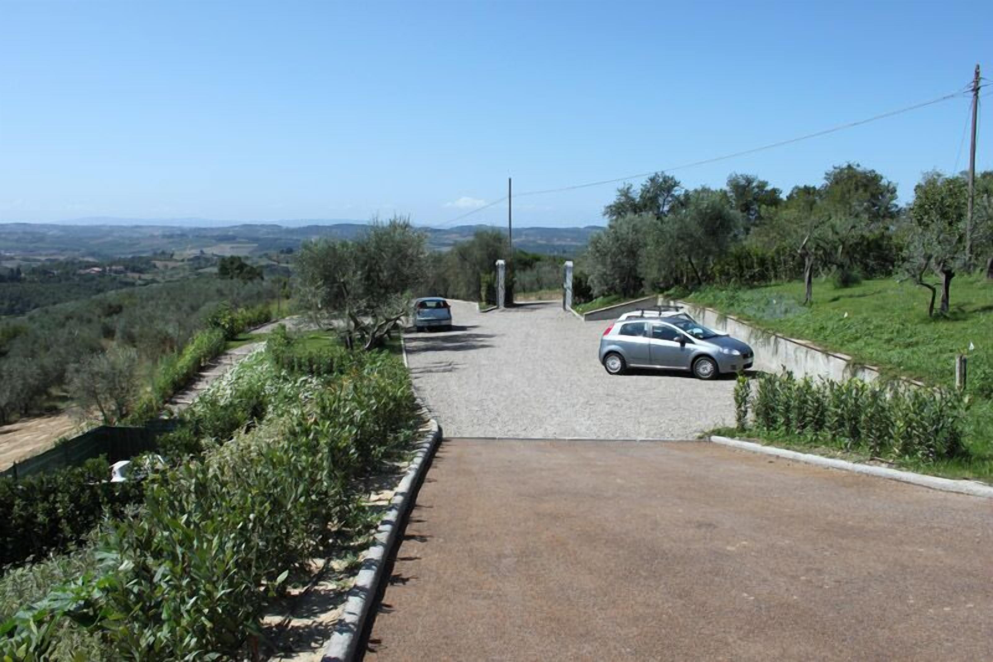 Un camino rural con autos estacionados y vistas al campo.