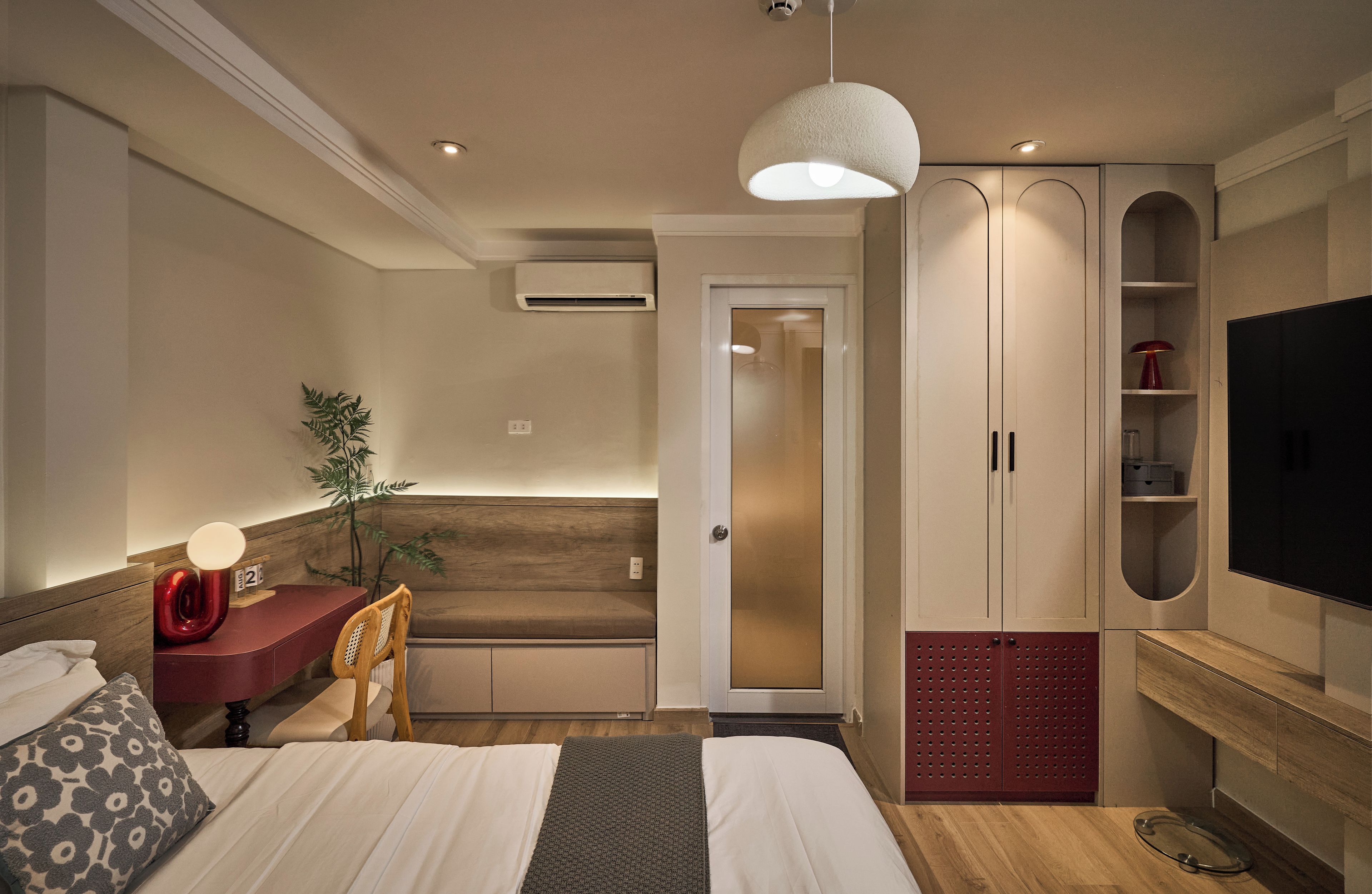 A hotel room with a bed, a desk, a chair, a television, and a wardrobe.