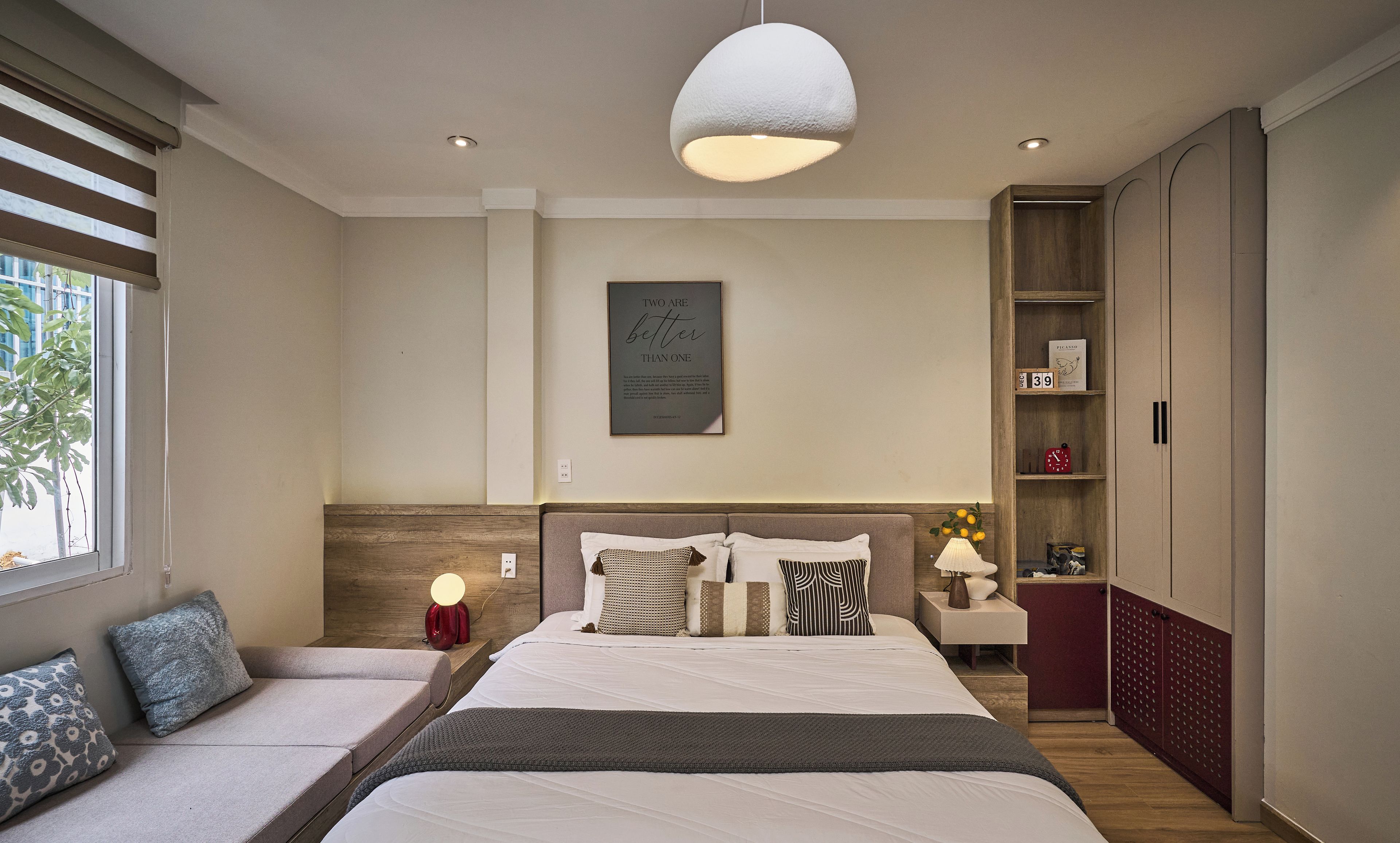 Un dormitorio moderno con una cama grande, dos mesitas de noche, una lámpara de noche y una estantería en la pared.