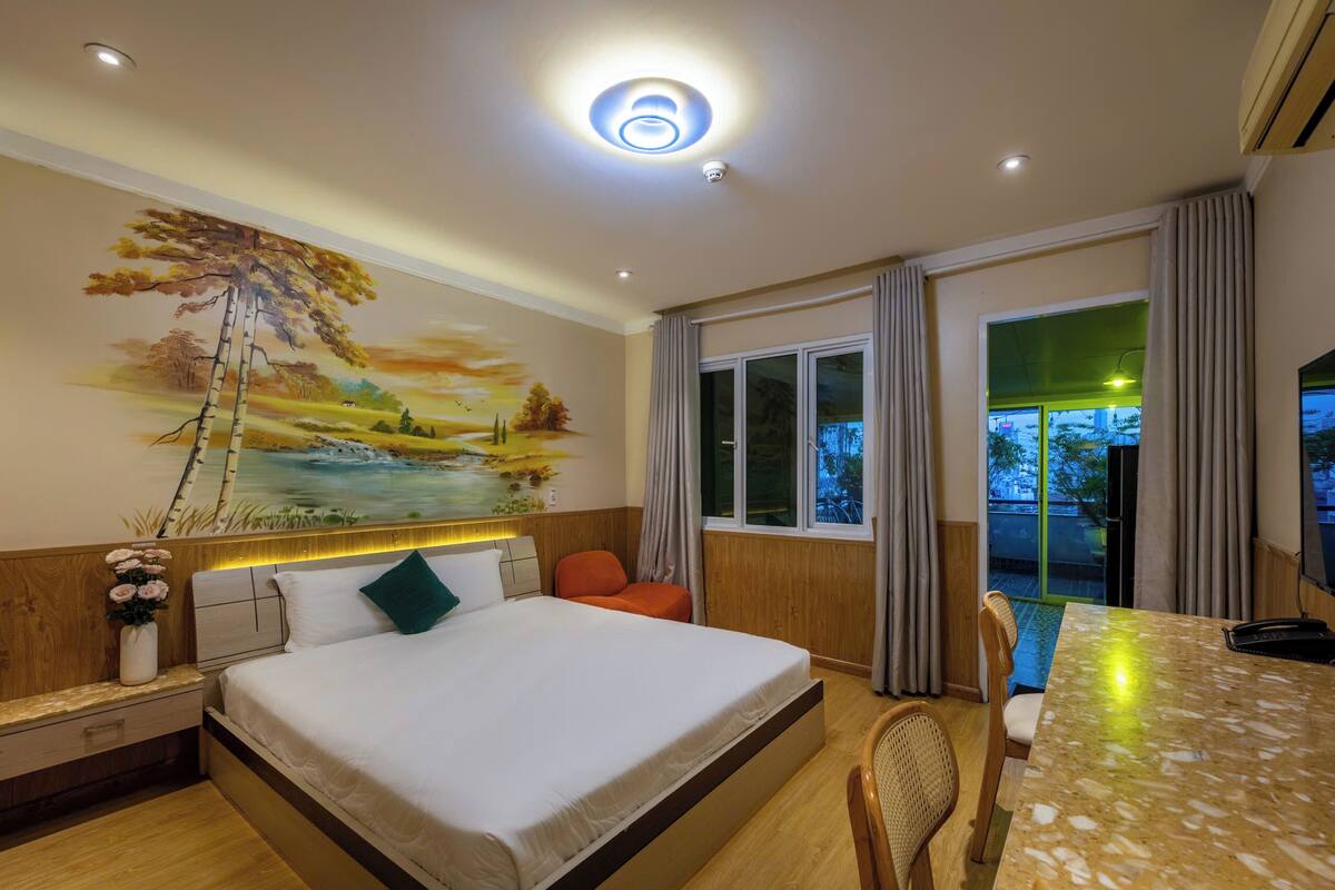 Habitación de hotel con una cama grande, una mesa de comedor, vistas al exterior y un mural en la pared.