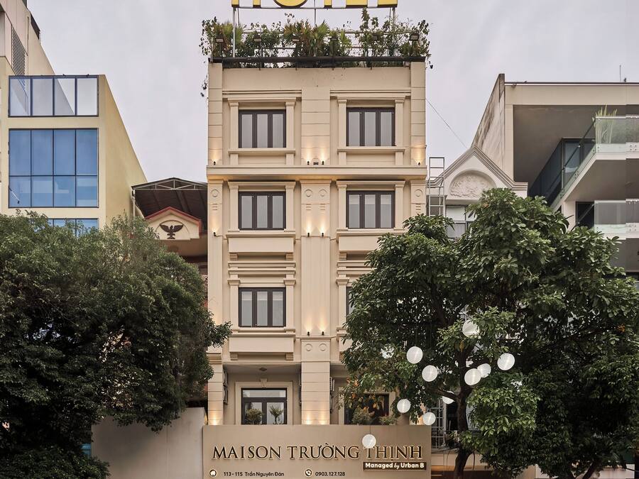 A hotel with a prominent 'HOTEL' sign at the top, a name sign below, and a modern facade with large windows and balconies.