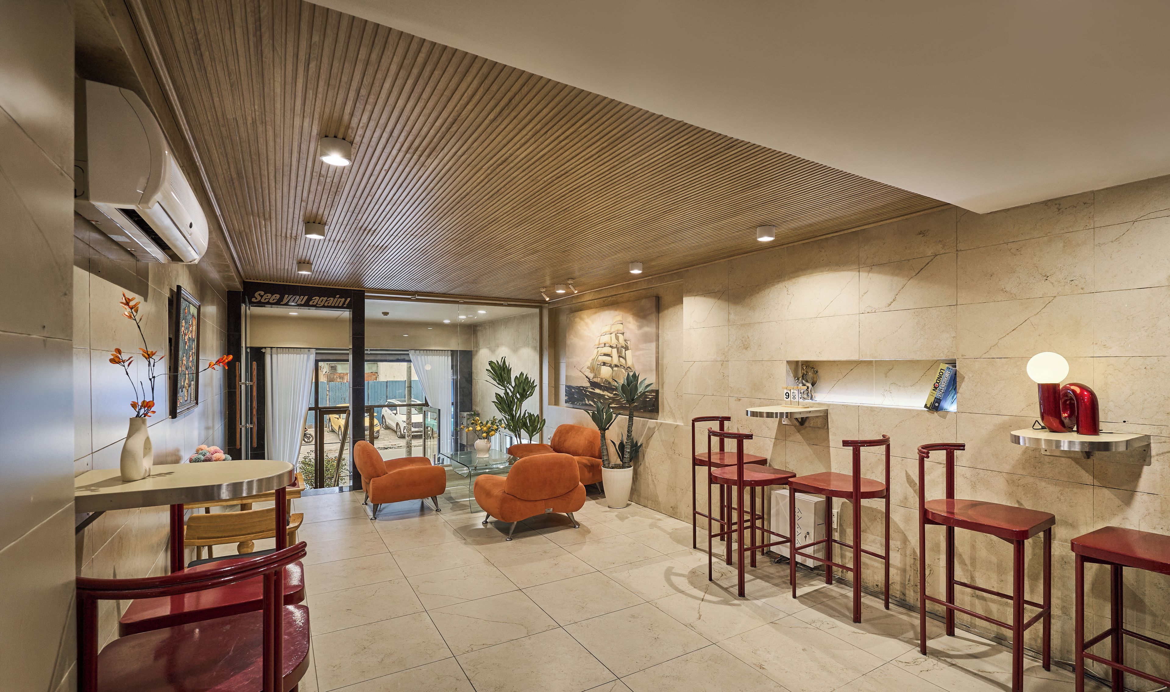 A hotel lobby with a wooden ceiling, a bar area with stools, and a seating area with chairs.