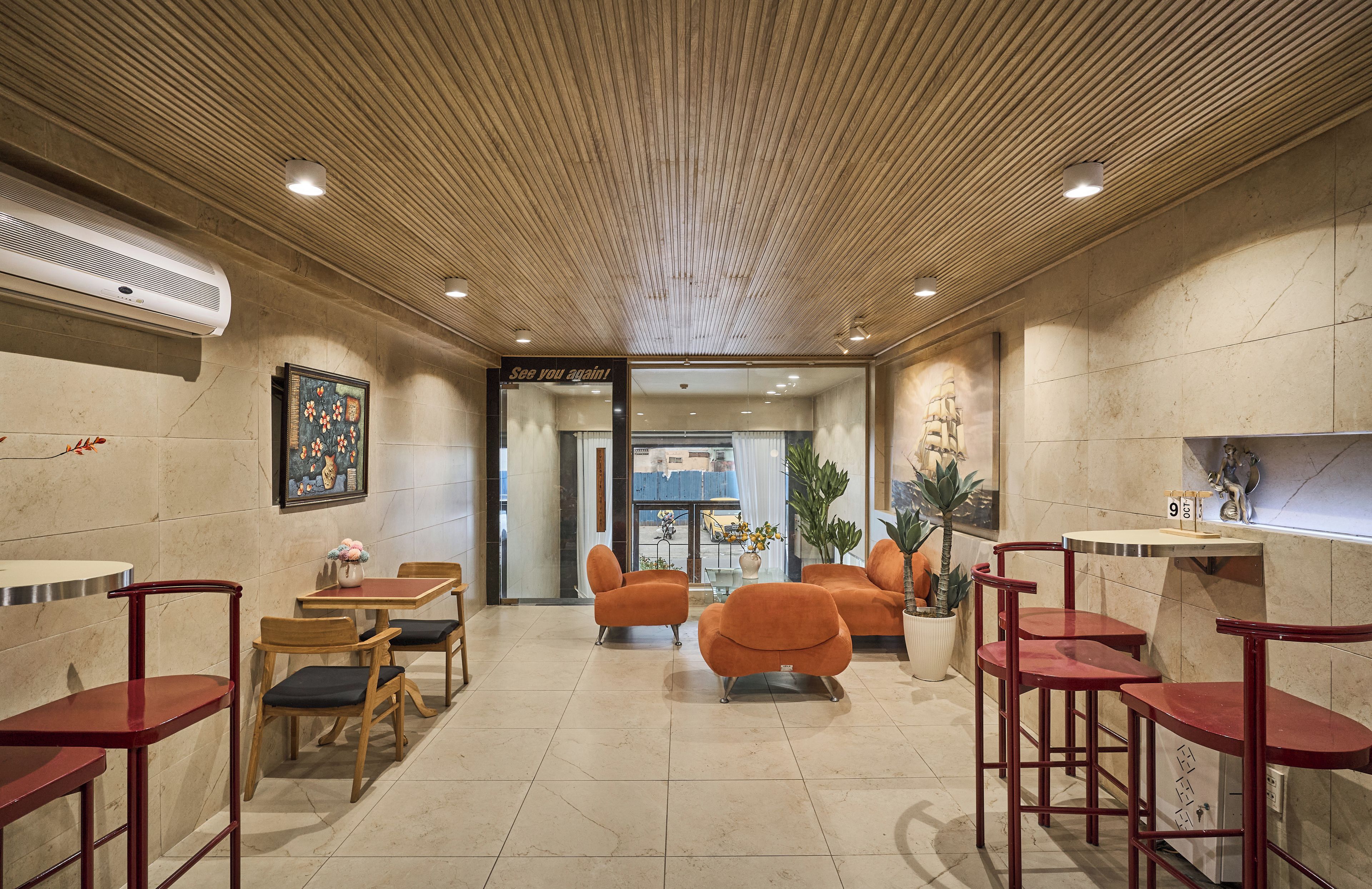 Um saguão de hotel com teto alto, piso em azulejos e diversos assentos, incluindo cadeiras e sofás.