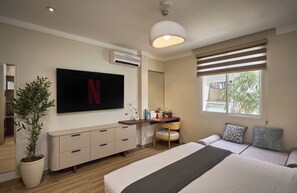 A modern bedroom with a flat-screen TV, a desk, a chair, a bed, and a large window. - Maison Truong Thinh Hotel by Urban B (Ho Chi Minh City)