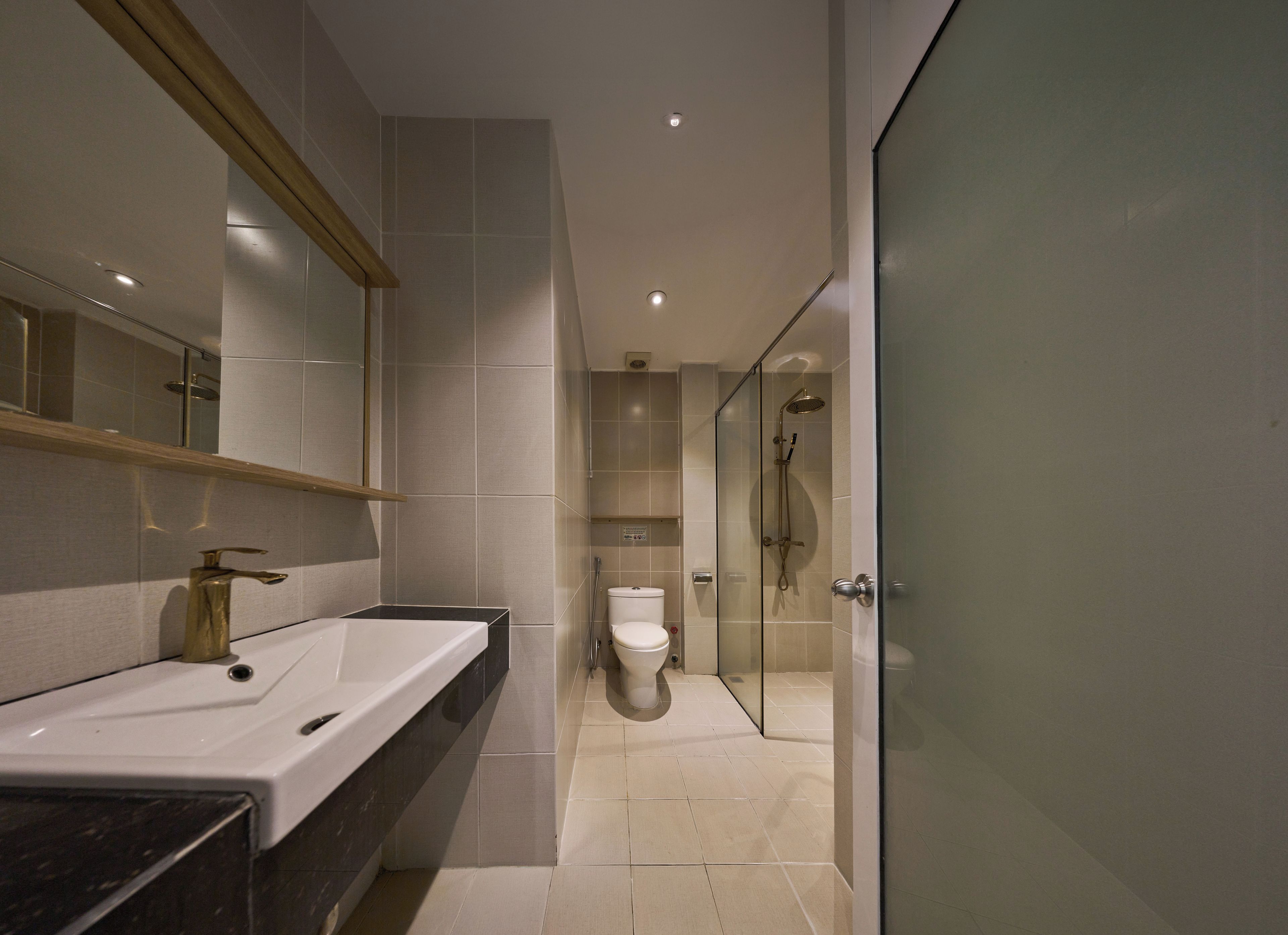 A modern bathroom with a large mirror, dual sinks, a toilet, and a glass-enclosed shower area.