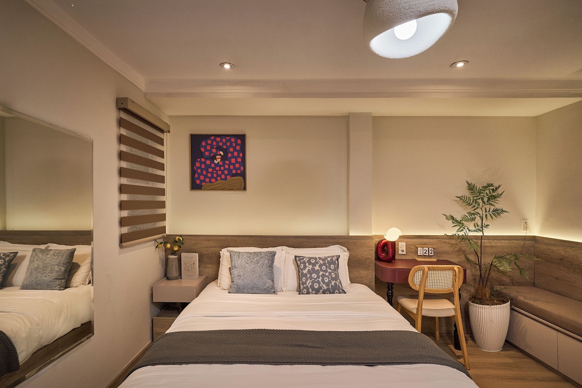 A modern bedroom with a large bed, bedside tables, a desk, and a chair.
