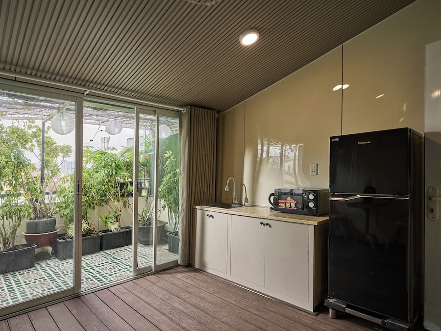 A modern kitchen with a black refrigerator, a microwave, and a sink. There is a sliding glass door leading to a patio with potted plants.