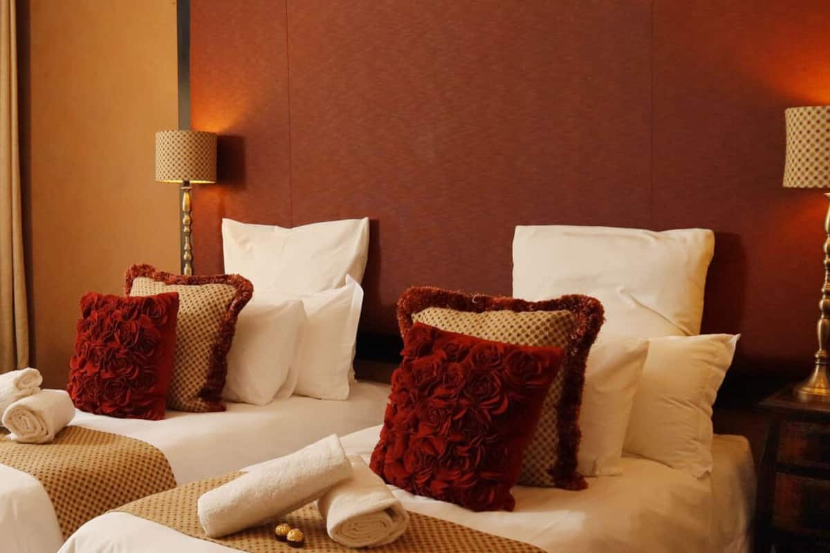 Een hotelkamer met twee bedden, een slaapbank en een nachtkastje.