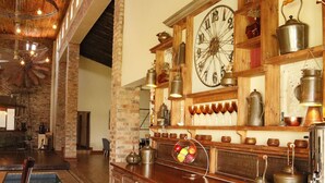 A rustic interior with exposed brick walls, wooden beams, and a large wall clock. - Water on Waldrift (Vereeniging)