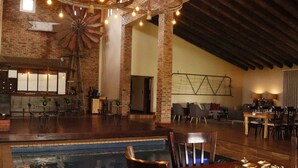 A spacious indoor area with a pool, seating arrangements, and a rustic brick wall. - Water on Waldrift (Vereeniging)
