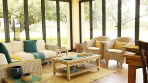 A spacious living area with a sofa, chairs, and a coffee table, featuring large windows and a view of greenery outside. - Water on Waldrift (Vereeniging)
