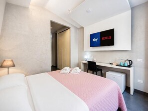 A hotel room with a bed, desk, chair, and a television displaying Sky and Netflix logos. - Le Vie del Vaticano (Rome)