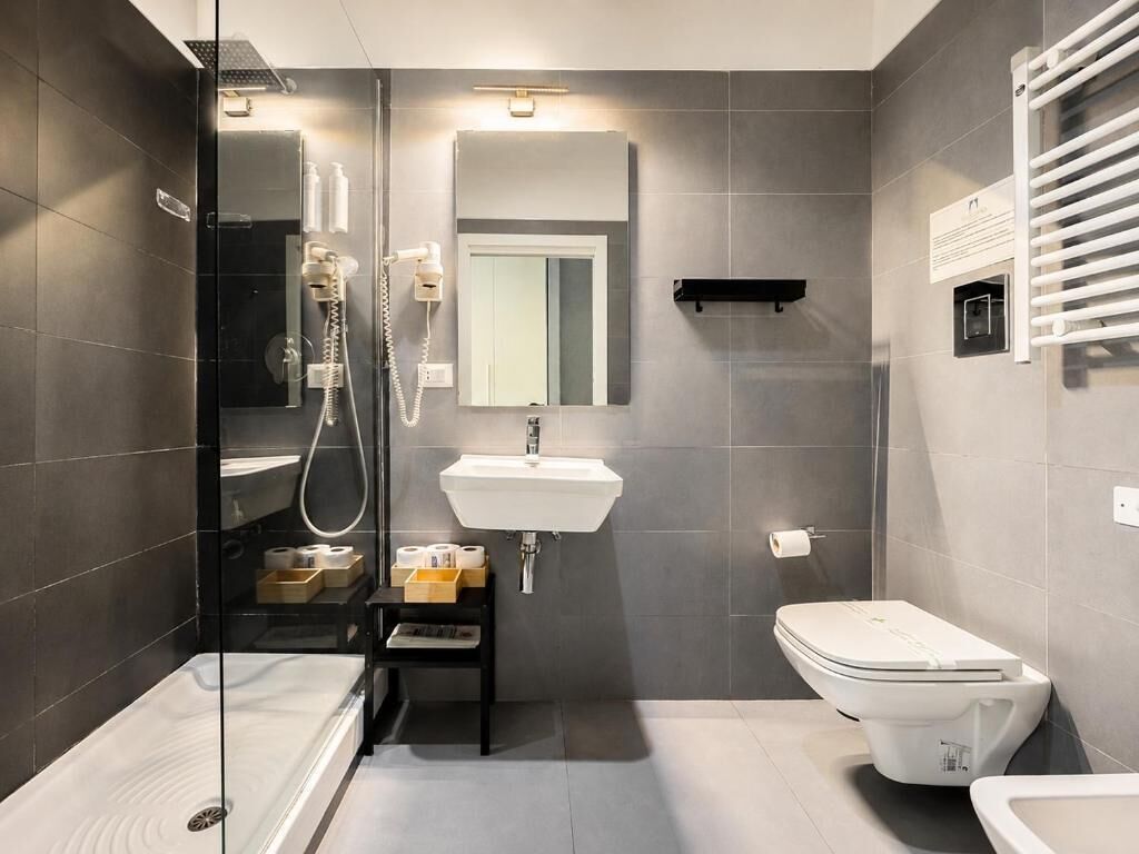 A modern bathroom with a glass-enclosed shower, a white sink, and a toilet.