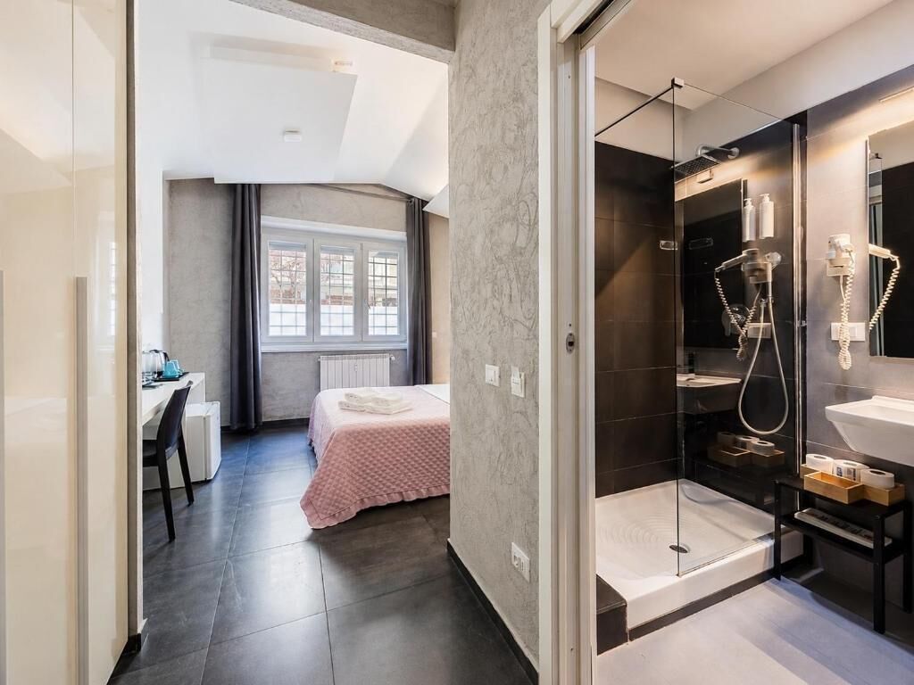 A modern bathroom with a glass shower enclosure, a separate sink area, and a visible window.
