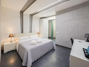 A modern hotel room with a bed, bedside tables, a desk, and a shower area. - Le Vie del Vaticano (Rome)