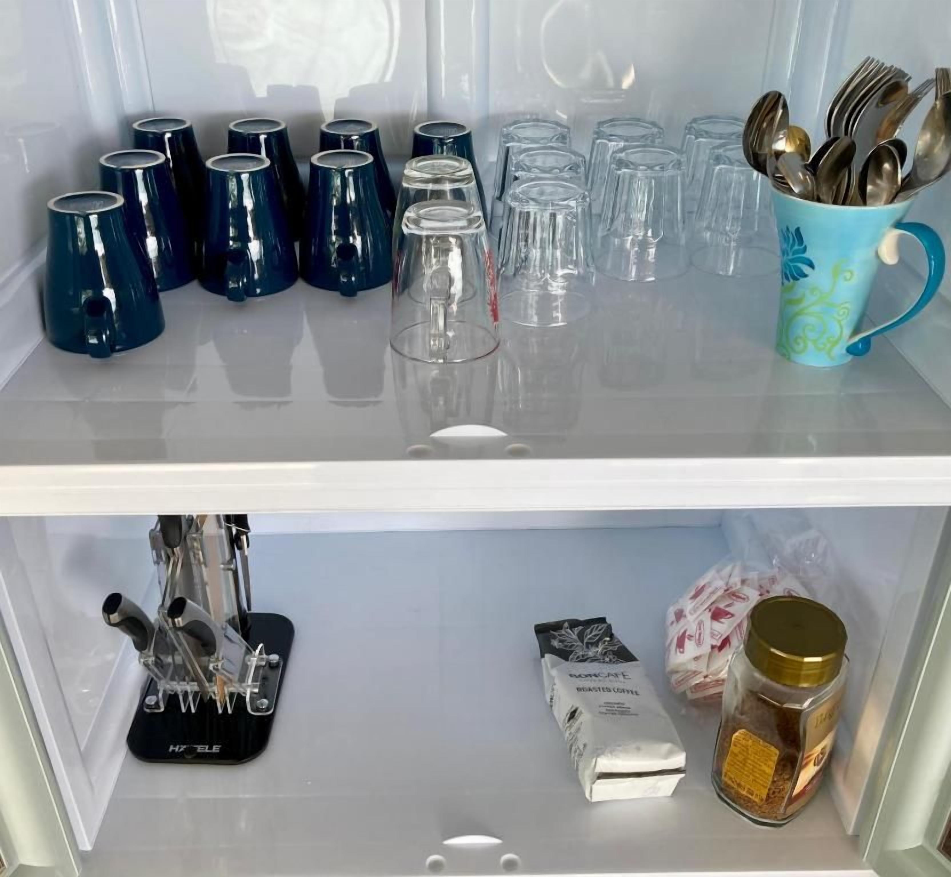 A kitchen shelf with various items including mugs, glasses, and a coffee machine.