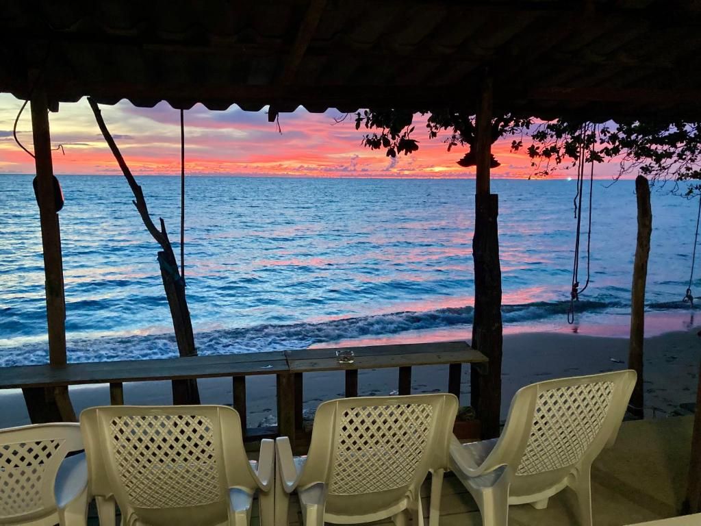 A beachside seating area with a view of the ocean and a sunset.