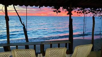 A beachside seating area with a view of the ocean and a sunset.