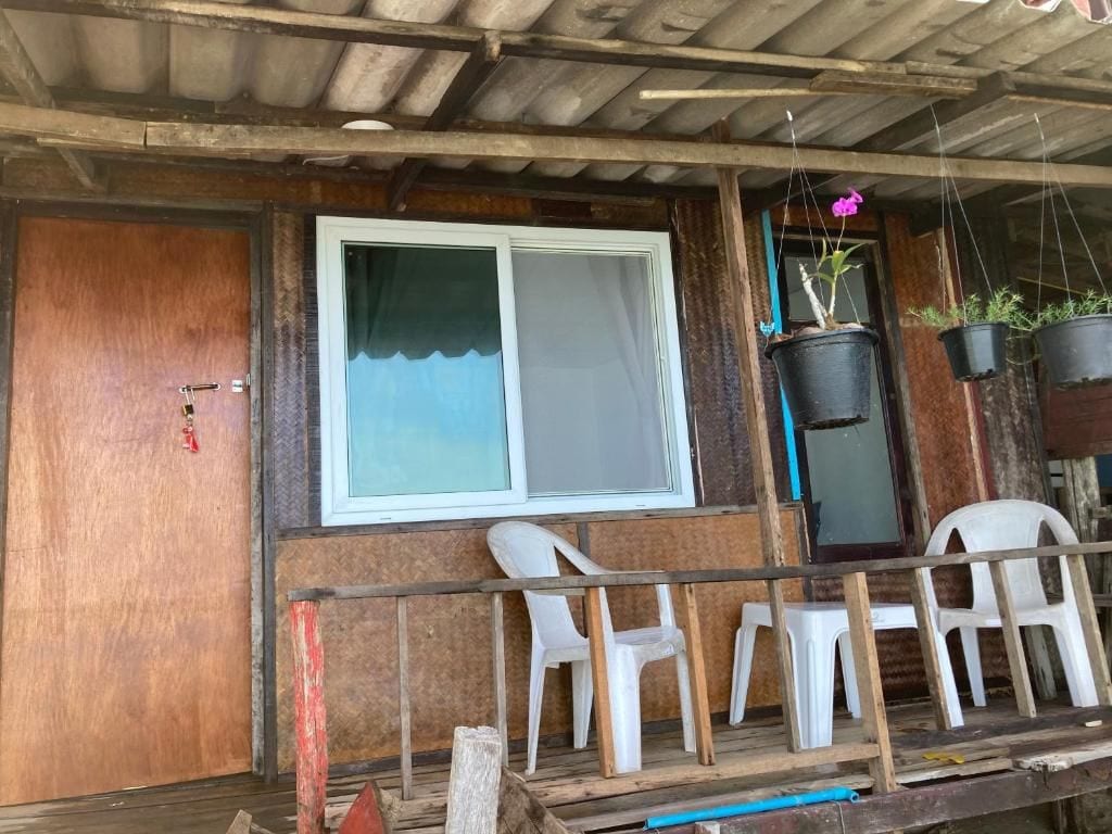 Ein Holzgebäude mit Fenster, einer Tür und einer Veranda mit Plastikstühlen.