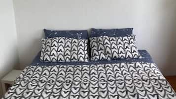 A bed with a patterned bedspread and two pillows with a geometric design.
