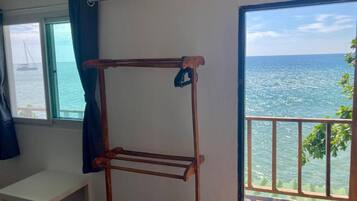 A room with a metal drying rack, a small table, and a view of the sea through a balcony door.