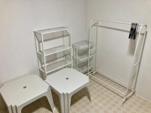 A room with a white metal shelving unit, two white stools, and a white metal rack with a barcode. - Ban Na White Sand Beach (Ko Chang)